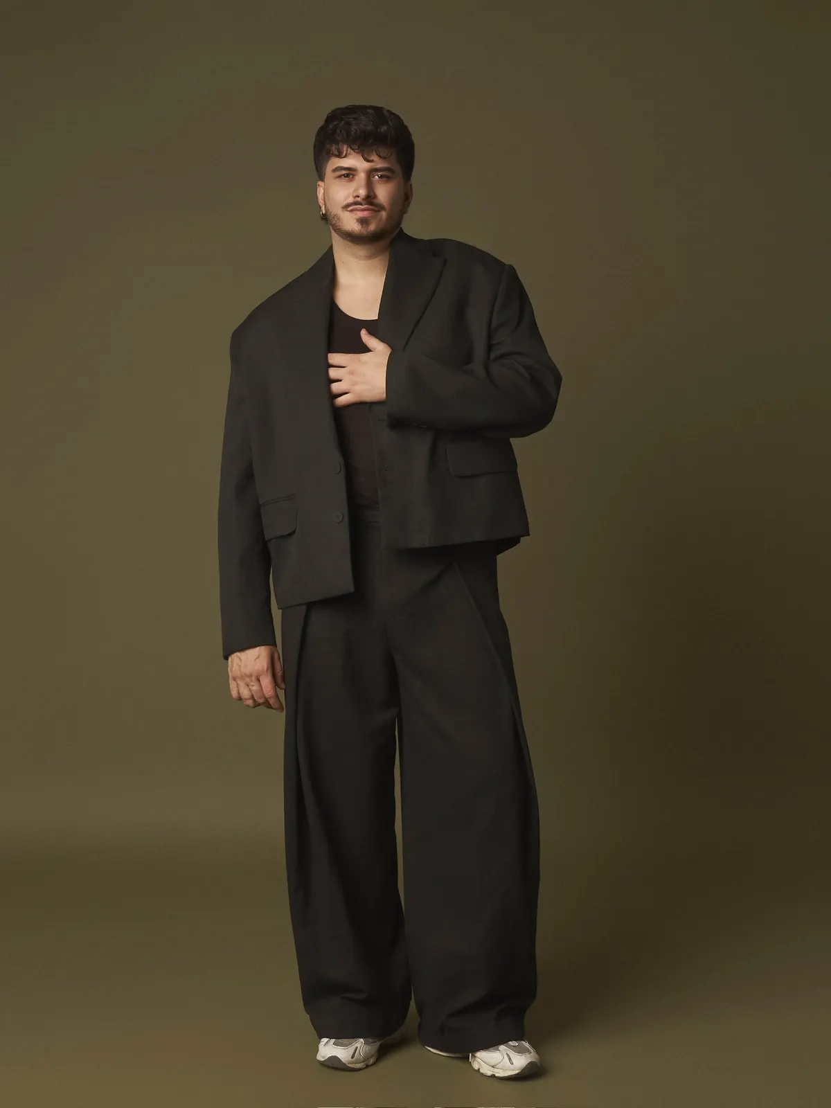 Iván Henríquez — traje oscuro sobre fondo verde oliva, mano en el pecho