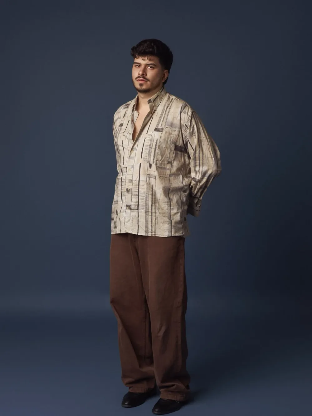 Iván Henríquez, cuerpo entero con camisa estampada sobre fondo azul