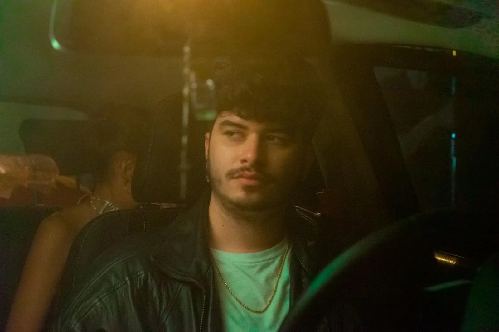 Iván Henríquez en rodaje — escena nocturna en un coche con luces de colores