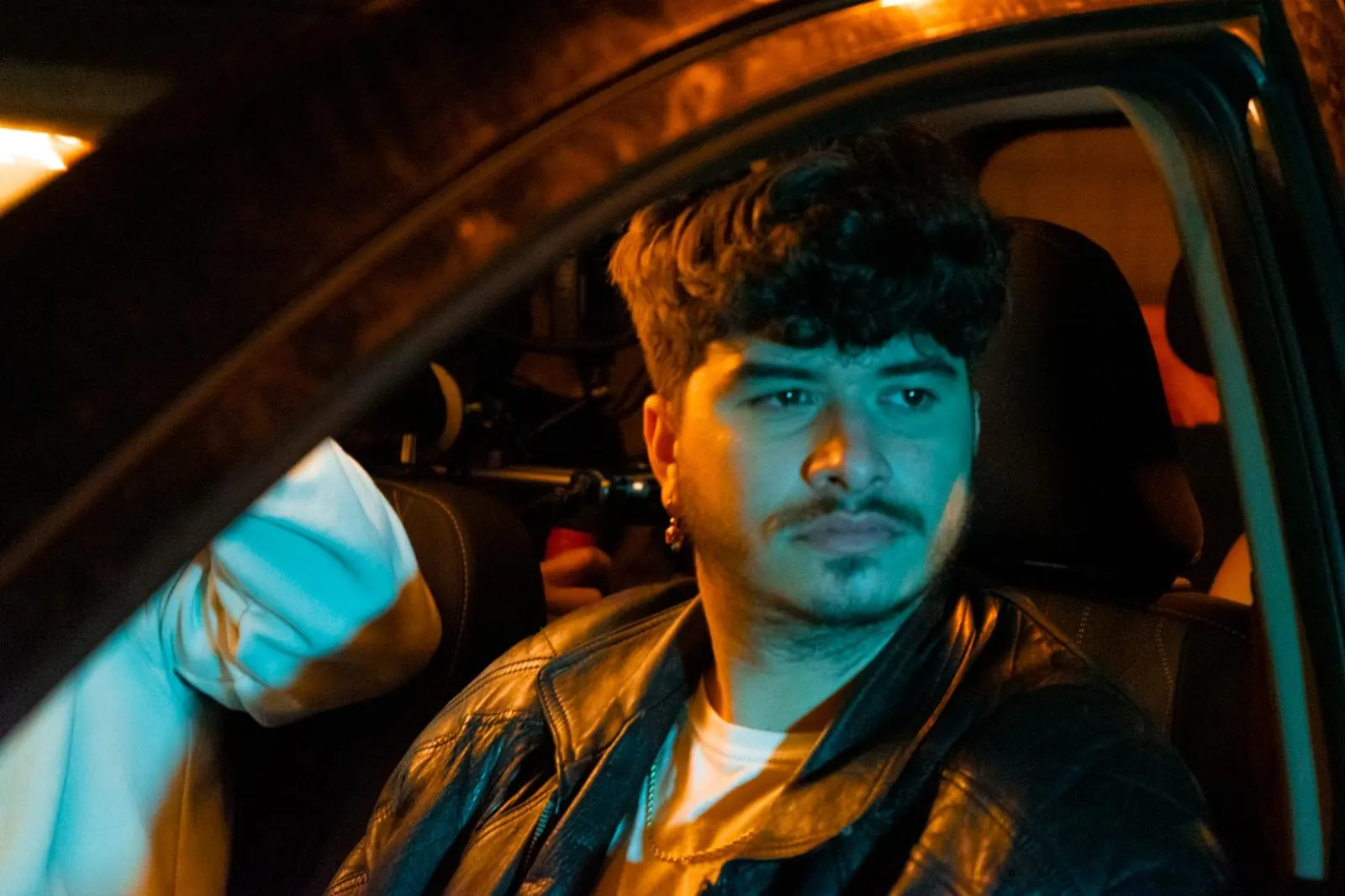 Iván Henríquez en rodaje — escena nocturna en un coche con luz cálida